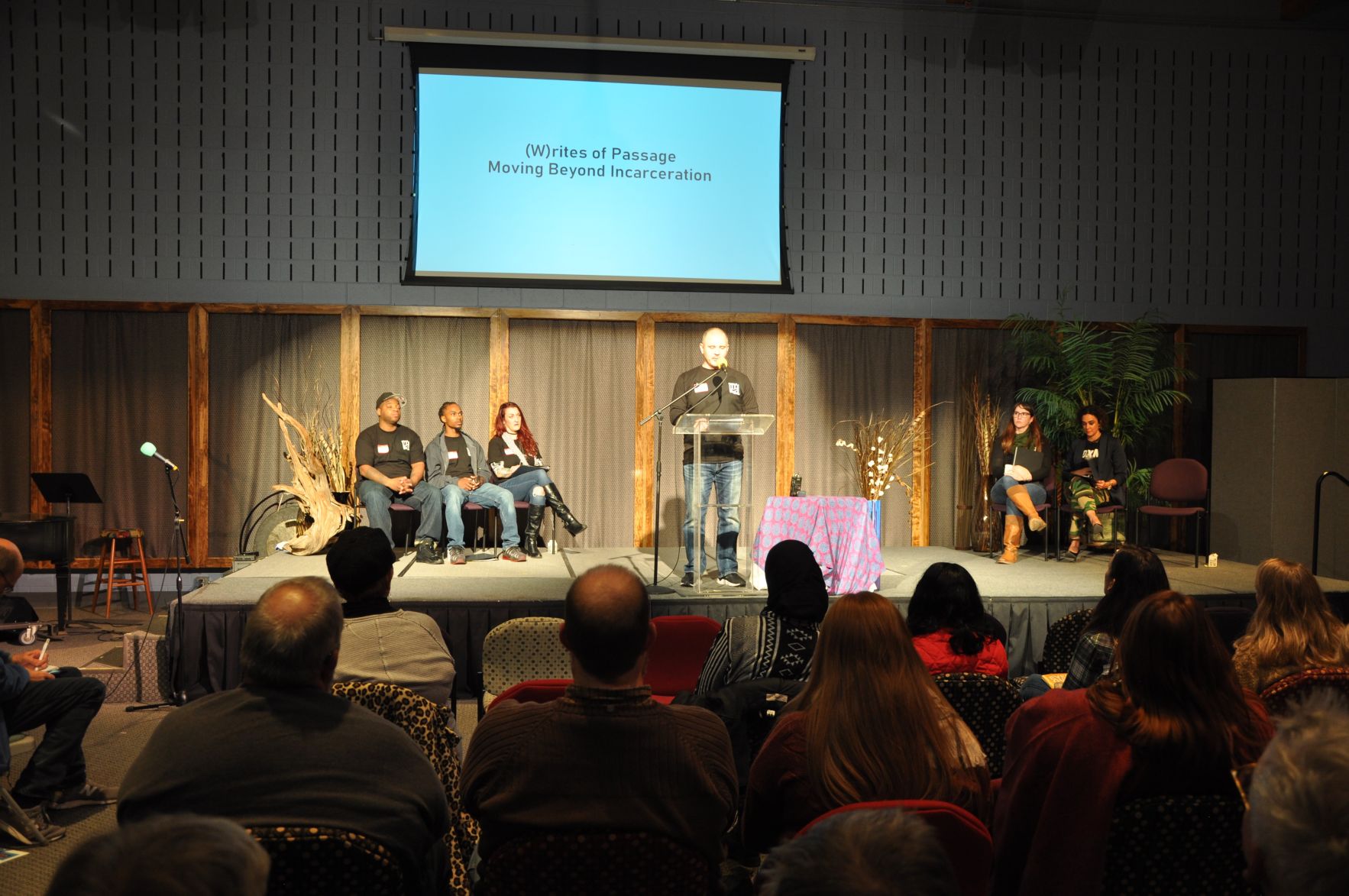 Emcee David Gaspar at podium during (W)rites of Passage
